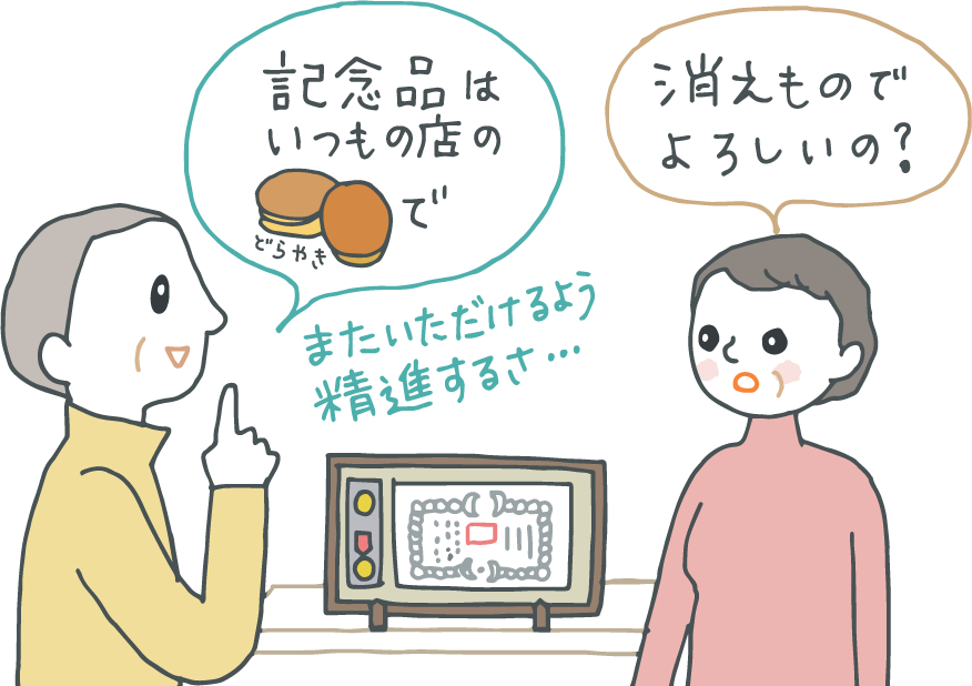 イラスト：初老の夫と妻。「記念品はいつものどら焼きで」と夫が言うと、妻が「消えものでよろしいの？」夫は「またいただけるよう精進するさ」とおおらかに笑う